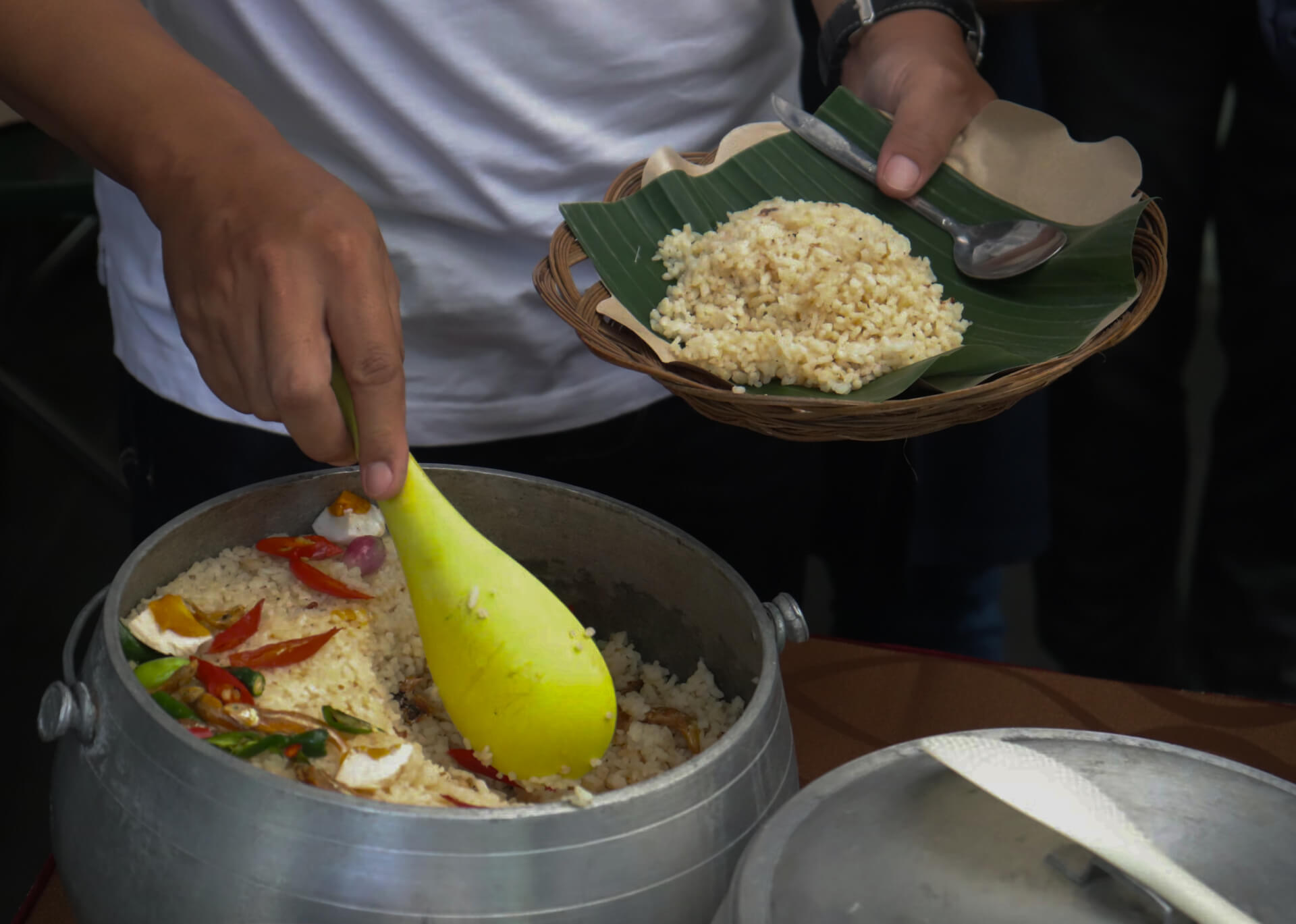 Traditional rice cooking in bamboo steamer with yellow spoon